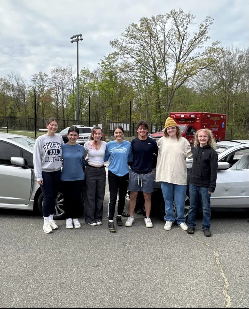 Participants in the mock drunk driving presentation pose for a photo with police officers.