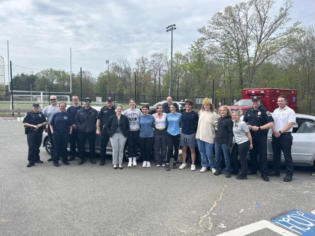 Participants in the mock drunk driving presentation pose for a photo with police officers.